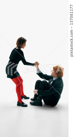 Woman helping seated man stand up holding his hand on white studio background. 137081177