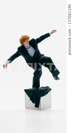 Businessman losing balance on pedestal in formal suit on white studio background. Businessman losing balance on pedestal in formal suit on white studio background. 137081190