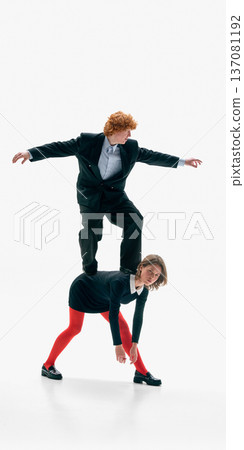 Man standing on womans back with arms stretched for balance on white studio background. 137081192