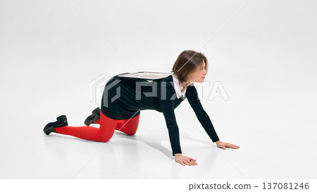 Woman in black dress and red tights crawling on white background in minimalist studio Woman in black dress and red tights crawling on white background in minimalist studio 137081246