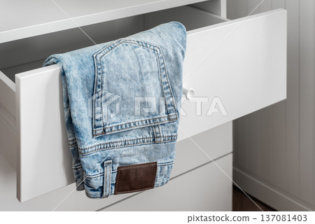 Denim jeans in open white drawer, home organization concept 137081403