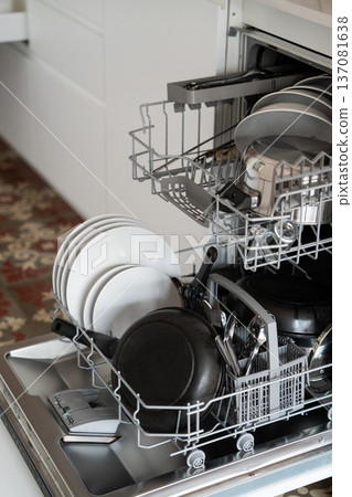 Dishwasher rack full of dirty dishes, plates, frying pan, and cutlery, ready for a wash cycle in a modern kitchen, illustrating efficiency and daily household chores Dishwasher rack full of dirty dishes, plates, frying pan, and cutlery, ready for a wash cycle in a modern kitchen, illustrating efficiency and daily household chores 137081638