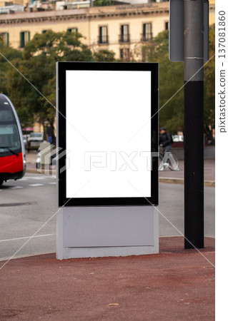 White empty commercial advertisement billboard standing on a city street, offering versatile space for branding and campaign promotion, with a red tram passing by 137081860