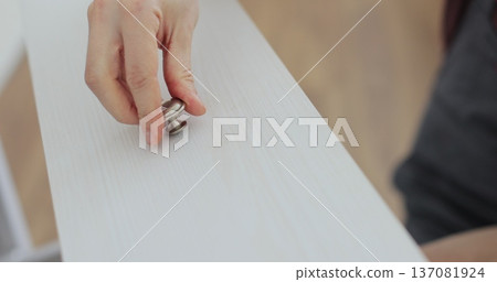 A young craftsman assembles furniture fittings. Professional furniture assembling. Installation of new furniture. Furniture assembly. 137081924
