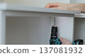 Close-up of person driving screw with cordless drill into furniture panel, assembling drawer. 137081932