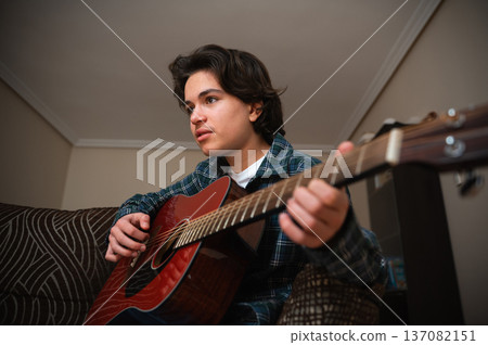 Teenager Playing Acoustic Guitar At Home In Casual Flannel Shirt 137082151