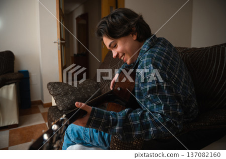 Teenage Boy Playing Acoustic Guitar At Home In Cozy Living Room 137082160