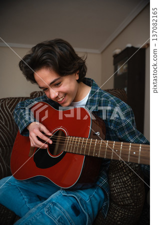 Teenage Boy Playing Acoustic Guitar at Home in Cozy Casual Setting 137082165