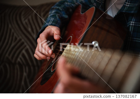 Teenage Boy Playing Acoustic Guitar At Home Strumming Music In Cozy Casual Interior Teenage Boy Playing Acoustic Guitar At Home Strumming Music In Cozy Casual Interior 137082167