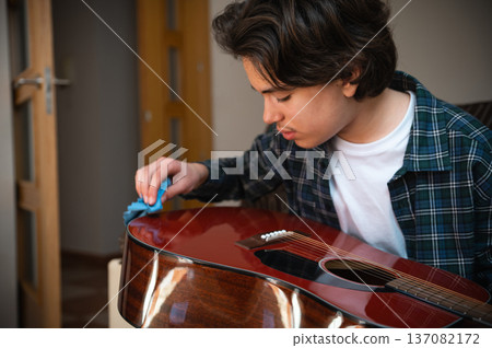 Teenage Boy Playing Acoustic Guitar At Home In Cozy Interior Practicing Music Teenage Boy Playing Acoustic Guitar At Home In Cozy Interior Practicing Music 137082172
