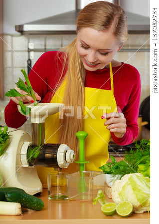 Woman in kitchen making vegetable smoothie juice 137082733