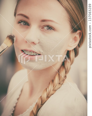 Woman applying with brush clay mud mask to her face Woman applying with brush clay mud mask to her face 137083289