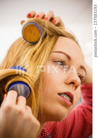 Woman curling her hair using rollers Woman curling her hair using rollers 137083293