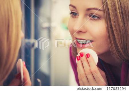 Woman using cotton pad to remove make up Woman using cotton pad to remove make up 137083294
