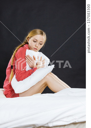 Sad depressed girl in bed gripping pillow Sad depressed girl in bed gripping pillow 137083300
