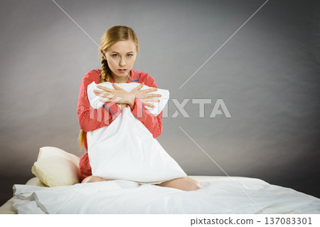 Sad depressed girl in bed gripping pillow Sad depressed girl in bed gripping pillow 137083301