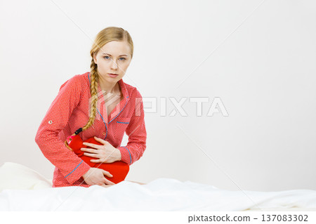 Woman feeling stomach cramps lying on bed 137083302
