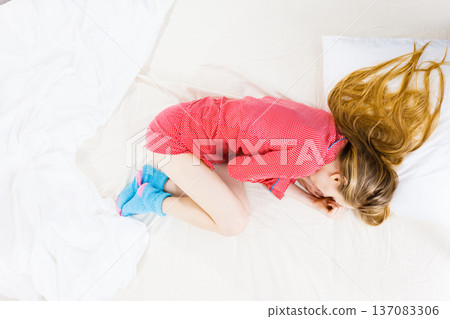 Young woman lying on bed wearing pajamas Young woman lying on bed wearing pajamas 137083306