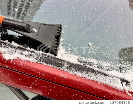 a man cleans a car with a scraper in winter 137084568
