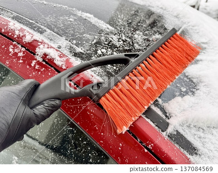car brush with a scraper in black and orange on a background of snow-white snow on a car in winter car brush with a scraper in black and orange on a background of snow-white snow on a car in winter 137084569