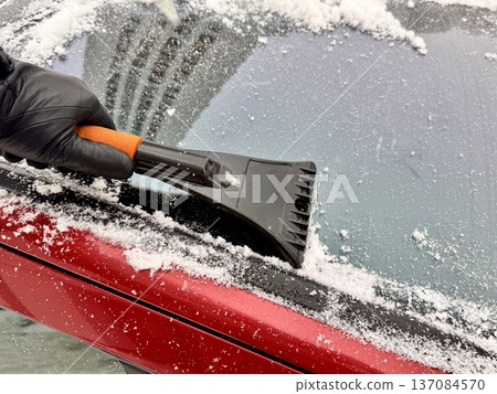 a man cleans a car with a scraper in winter a man cleans a car with a scraper in winter 137084570