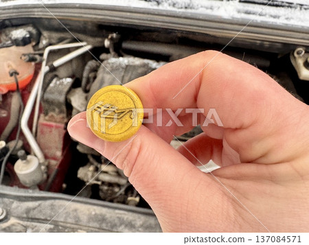 the girl independently checks the oil level in the engine in her personal car and adds a small amount from the bottle. 137084571
