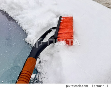 car brush with a scraper in black and orange on a background of snow-white snow on a car in winter car brush with a scraper in black and orange on a background of snow-white snow on a car in winter 137084591