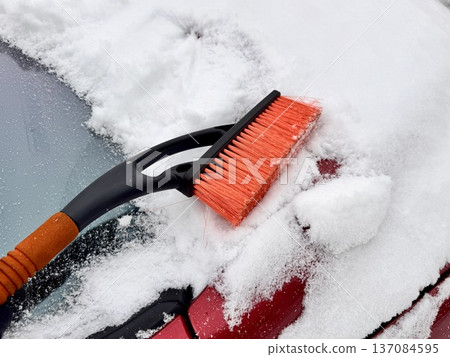 car brush with a scraper in black and orange on a background of snow-white snow on a car in winter car brush with a scraper in black and orange on a background of snow-white snow on a car in winter 137084595