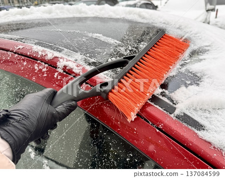 car brush with a scraper in black and orange on a background of snow-white snow on a car in winter car brush with a scraper in black and orange on a background of snow-white snow on a car in winter 137084599