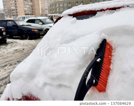 car brush with a scraper in black and orange on a background of snow-white snow on a car in winter car brush with a scraper in black and orange on a background of snow-white snow on a car in winter 137084629