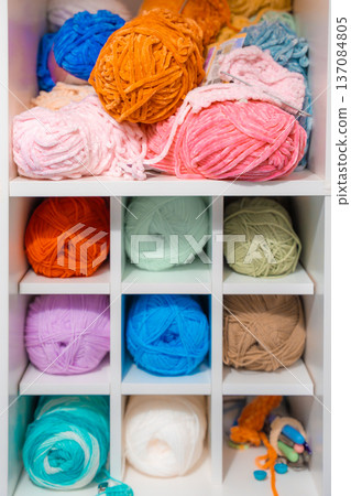 Multicolored yarn balls organized in white shelving unit for knitting and crochet storage 137084805