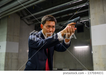 A man in a suit holds a gun A man in a suit holds a gun 137084831