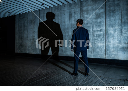 A man in a suit confronting a shadow A man in a suit confronting a shadow 137084951