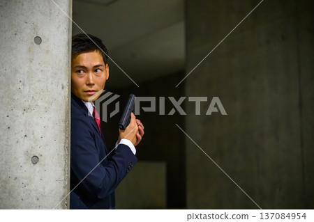 A man in a suit holds a gun 137084954