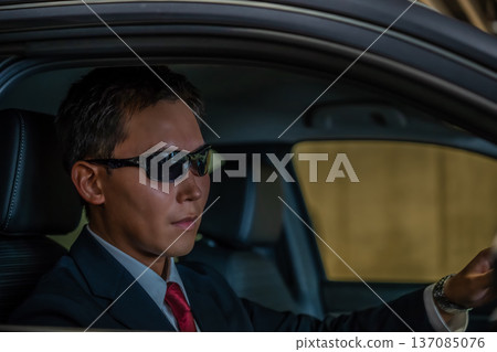 A man in a suit in the driver's seat 137085076
