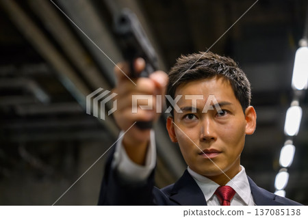 一名身穿西裝的男子手持一把槍 一名身穿西裝的男子手持一把槍 137085138