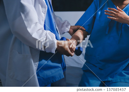 Physical therapist giving stretching exercises with elastic exercise bands and physical therapist hands helping male patient Physical therapy concept Physical therapist giving stretching exercises with elastic exercise bands and physical therapist hands helping male patient Physical therapy concept 137085437