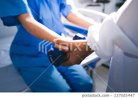 Physical therapist giving stretching exercises with elastic exercise bands and physical therapist hands helping male patient Physical therapy concept 137085447