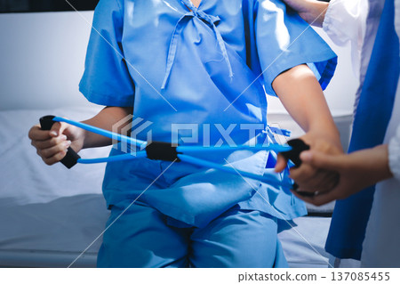 Physical therapist giving stretching exercises with elastic exercise bands and physical therapist hands helping male patient Physical therapy concept 137085455