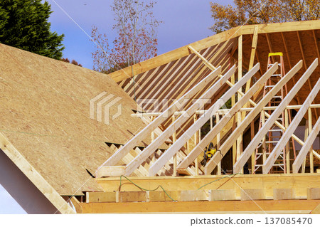 Workers are building roof using wooden beams sheets in residential location Workers are building roof using wooden beams sheets in residential location 137085470