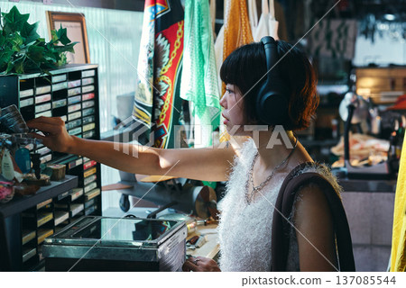 一位年輕女子正在一家擺滿復古物品的古董店購物。 137085544