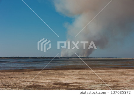 A distant wildfire sends a towering column of smoke into the sky above a small coastal island near Vlora, Albania, captured on August 25, 2025.  137085572