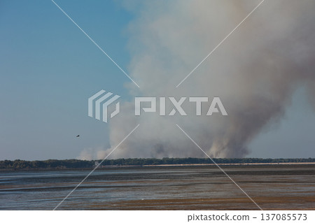 A distant wildfire sends a towering column of smoke into the sky above a small coastal island near Vlora, Albania, captured on August 25, 2025.  137085573