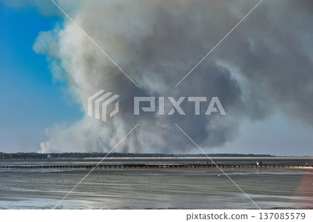 A distant wildfire sends a towering column of smoke into the sky above a small coastal island near Vlora, Albania, captured on August 25, 2025.  137085579