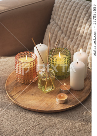 Candles and Reed Diffuser on Wooden Tray. Cozy Home Decor lifestyle with Cushions Candles and Reed Diffuser on Wooden Tray. Cozy Home Decor lifestyle with Cushions 137085689