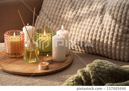 Candles and Reed Diffuser on Wooden Tray. Cozy Home Decor lifestyle with Cushions Candles and Reed Diffuser on Wooden Tray. Cozy Home Decor lifestyle with Cushions 137085690