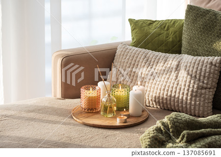Candles and Reed Diffuser on Wooden Tray. Cozy Home Decor lifestyle with Cushions Candles and Reed Diffuser on Wooden Tray. Cozy Home Decor lifestyle with Cushions 137085691