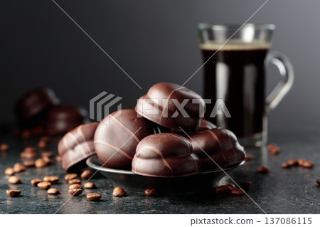 Chocolate-covered coffee cookies and cup of black coffee. Chocolate-covered coffee cookies and cup of black coffee. 137086115