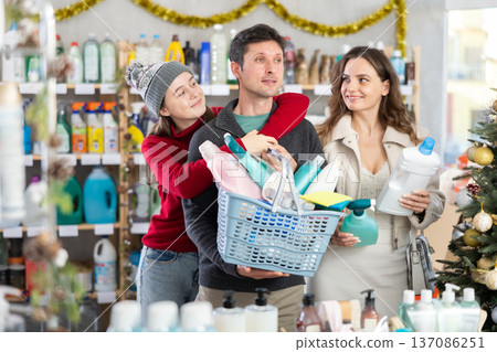 Couple man and woman with daughter chooses household chemicals in decorated store Couple man and woman with daughter chooses household chemicals in decorated store 137086251