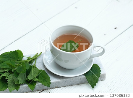 A cup of fresh tea from Melissa officinalis, commonly known as lemon balm or melissa on a marble. 137086383